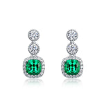Cushion-cut emerald drop earrings crafted for brilliance and emotional harmony.