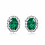 Oval emerald stud earrings with white halo, representing grace and wisdom.
