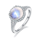Round moonstone jewelry ring surrounded by sparkling accents, representing emotional purity.