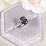 Halo alexandrite ring reflecting dual light and transformation, handcrafted by Minerva Jewelry.