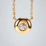 Single round moissanite in a bezel setting with the chain connected at both sides.