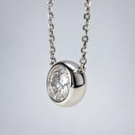 Single round moissanite in a bezel setting with the chain connected at both sides.