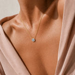 Round moissanite solitaire necklace with a four-prong setting and chain attached at both sides.