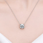 Round moissanite solitaire necklace with a four-prong setting and chain attached at both sides.