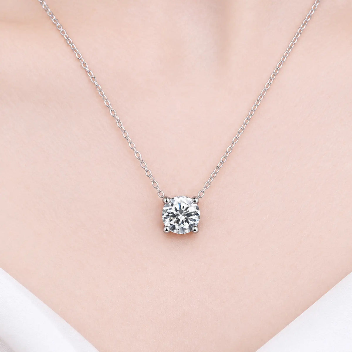 Round moissanite solitaire necklace with a four-prong setting and chain attached at both sides.