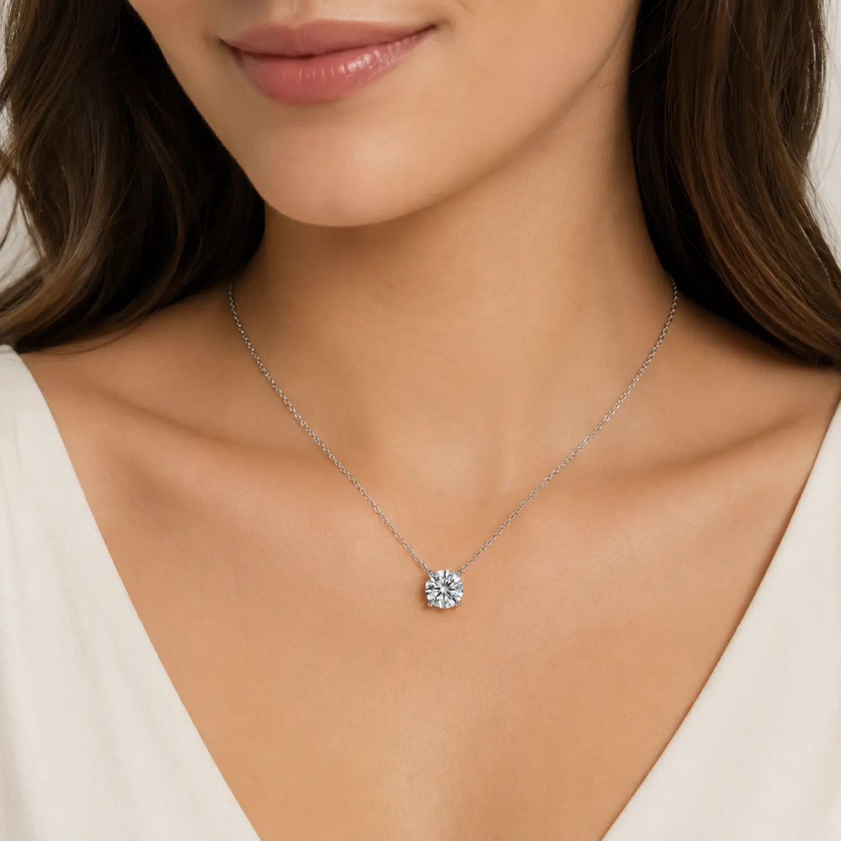 Round moissanite solitaire necklace with a four-prong setting and chain attached at both sides.