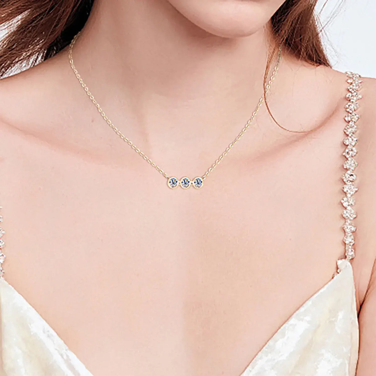 Three round moissanite stones in individual bezel settings arranged horizontally on a chain.